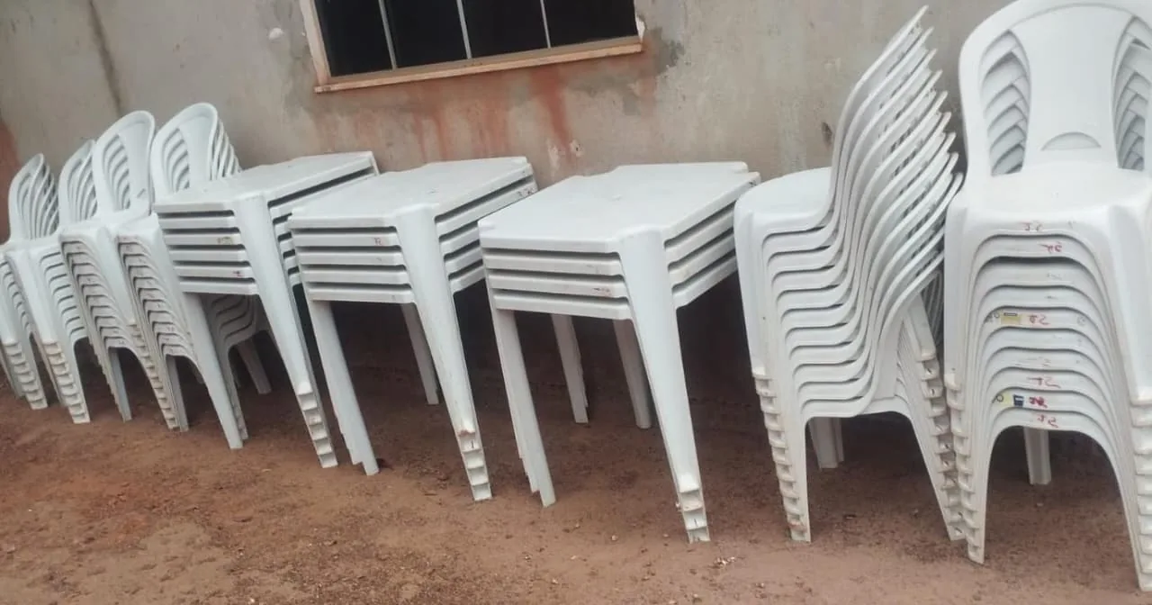 Mesas plásticas quadradas e cadeiras brancas empilhadas no pátio da loja